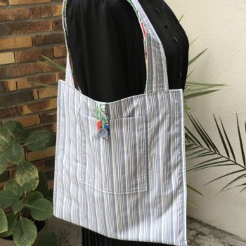 Sac fleuri, fleurs stylisées. Au verso la doublure est un tissu 100% coton à fines rayures bleues et grises signée QjuTie Kids Collection. Verso, doublure et poche.