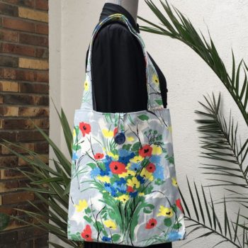 Sac fleuri, fleurs stylisées. Au recto le totebag présente une toile de coton texturé (barkcloth), un imprimé de bouquets de fleurs stylisées en rouge bleu jaune vert sur fond blanc et gris. Recto face A.