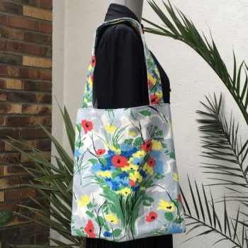 Sac fleuri, fleurs stylisées. Au recto le totebag présente une toile de coton texturé (barkcloth), un imprimé de bouquets de fleurs stylisées en rouge bleu jaune vert sur fond blanc et gris. Recto face B.