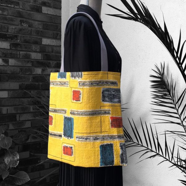 Tote bag design vintage, imprimé graphique, dessins en noir rouge bleu brun gris sur fond jaune moutarde.