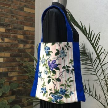 Sac en tissu de style bohème chic, Bazoches par Romanex de Boussac, dessin de Pascaline Villon, 1960s. Composition florale, branches fleuries, fleurs en bleu, gris, mauve, vert sur fond à larges rayures verticales en rose sur blanc. Recto face A.