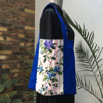 Sac en tissu de style bohème chic, Bazoches par Romanex de Boussac, dessin de Pascaline Villon, 1960s. Composition florale, branches fleuries, fleurs en bleu, gris, mauve, vert sur fond à larges rayures verticales en rose sur blanc. Recto face B.