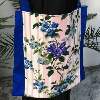 Sac en tissu de style bohème chic, Bazoches par Romanex de Boussac, dessin de Pascaline Villon, 1960s. Composition florale, branches fleuries, fleurs en bleu, gris, mauve, vert sur fond à larges rayures verticales en rose sur blanc. Recto face B.