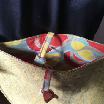 Sac bandoulière en obi japonais et tissu vintage. Au recto le sac présente une toile vintage en coton ou lin, au tissage rustique, une ancienne ceinture de kimono (obi) japonaise. Au verso la doublure est un fin tissu de coton à imprimé graphique, un motif de formes libres en jaune, rouge, vert, blanc et beige kaki. Exemplaire 2.