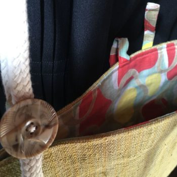 Sacoche en ceinture de kimono vintage. Au recto le sac présente une toile vintage en coton ou lin, au tissage rustique, un ancien obi japonais. Au verso la doublure est un fin tissu de coton à imprimé graphique, un motif de formes libres en jaune, rouge, vert, blanc et beige kaki. Détail du bouton en bakélite.