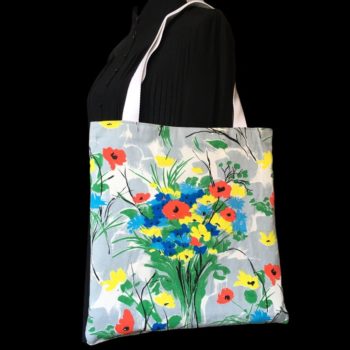 Totebag fleuri, à dessin de fleurs stylisées. Au recto le sac présente une toile de coton texturé (barkcloth), un imprimé de bouquets de fleurs stylisées en rouge bleu jaune vert sur fond blanc et gris.