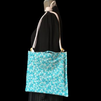 Sac bandoulière à imprimé fleuri, en tissu vintage. Au verso la doublure est un tissu 100% coton à motif de petites fleurs blanches sur fond bleu ciel.