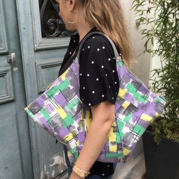 Cabas de forme triangulaire en tissu vintage des années 1950s début 1960s, toile d’ameublement en coton. Imprimé graphique, motifs géométriques abstraits, formes libres. Vu porté, de profil.