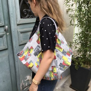 Cabas triangle en pliage origami, coupon vintage des années 1950s début 1960s, tissu souple avec effet texturé et satiné. Imprimé graphique, motifs géométriques abstraits époque moderne atomique milieu XXe siècle, dessins en noir rouge jaune vert gris sur fond gris clair. Vu porté.