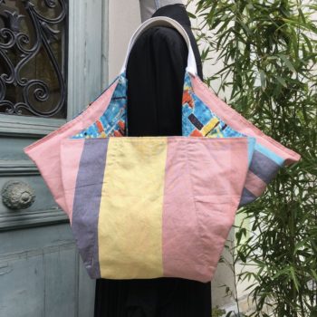 Cabas triangle pour femme, doublure à fines rayures verticales de couleur orange, jaune, bleue sur fond blanc.