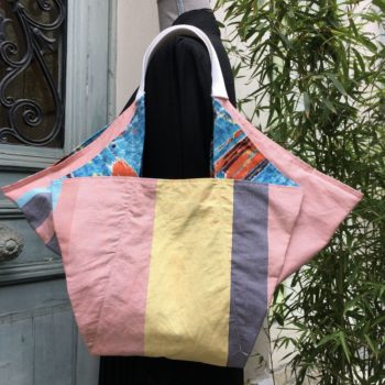 Cabas triangle pour femme, doublure à fines rayures verticales de couleur orange, jaune, bleue sur fond blanc.