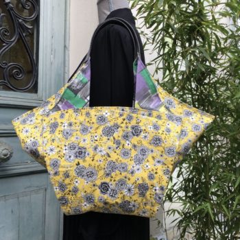 Cabas de forme triangulaire en tissu vintage, doublure à motifs floraux dessinés de traits noirs et gris sur fond jaune.