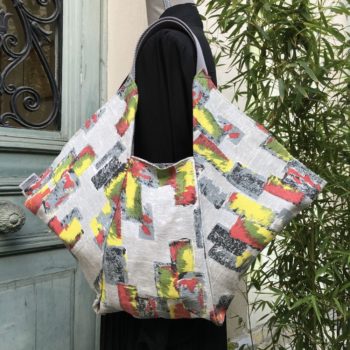 Cabas triangle en pliage origami, coupon vintage des années 1950s début 1960s, tissu souple avec effet texturé et satiné. Imprimé graphique, motifs géométriques abstraits époque moderne atomique milieu XXe siècle, dessins en noir rouge jaune vert gris sur fond gris clair. Recto face B.