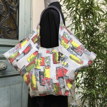 Cabas triangle en pliage origami, coupon vintage des années 1950s début 1960s, tissu souple avec effet texturé et satiné. Imprimé graphique, motifs géométriques abstraits époque moderne atomique milieu XXe siècle, dessins en noir rouge jaune vert gris sur fond gris clair. Recto face A.