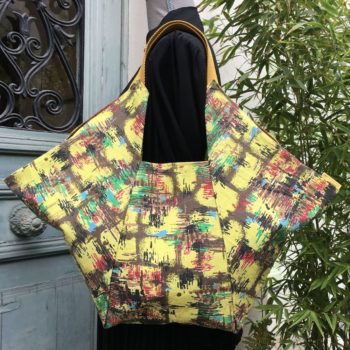 Cabas origami en tissu d’ameublement vintage revalorisé, imprimé de formes libres, motif abstrait multicolore en rouge, vert, bleu, noisette, brun bordé de noir sur fond jaune, recto face A.