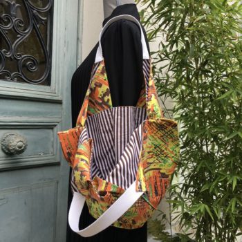 Sac origami en tissu vintage Marignan, imprimé de formes libres en orange, vert, brun et jaune, aplats de couleurs striés de noir, doublure rayures marron et blanc.