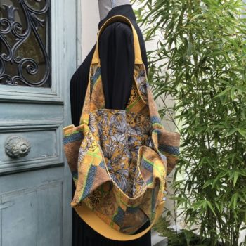 Sac de forme triangulaire, en tissu vintage des années 1950s début 1960s, imprimé graphique, motifs abstraits, et doublure à motif de feuillage tropical exubérant dessiné en traits noirs et gris sur fond ocre jaune.