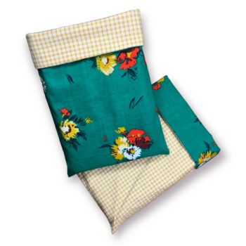 Housse à livre en tissu, à doublure vichy jaune moutarde, au recto imprimé de fleurs stylisées en ivoire, blanc, ocre jaune / jaune moutarde, rouge orangé et bordeaux sur fond vert turquoise.