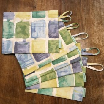 Pochette à fermeture éclair, trousse plate zippée, en toile d'ameublement vintage en coton, à imprimé de formes libres en vert, bleu, jaune, sur fond blanc cassé / écru.