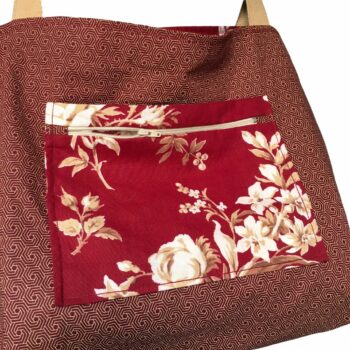 Sac cabas XL rouge bordeaux. Composition florale de type grisaille, grandes fleurs et branches de rosiers en blanc cassé / écru et beige sur fond rouge bordeaux. Verso, détail et poche intérieure zippée.