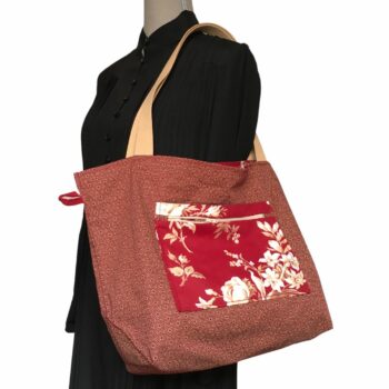 Sac cabas XL rouge bordeaux. Composition florale de type grisaille, grandes fleurs et branches de rosiers en blanc cassé / écru et beige sur fond rouge bordeaux. Verso, avec poche intérieure zippée.