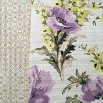 Toile d’ameublement vintage de la période 1940s 1950s, en coton. L’imprimé floral et champêtre déploie un dessin de pivoines en mauve et lilas, et de petites fleurs des champs jaunes (de type renoncule des prés). Le tissu, en coton épais, a une texture de fines rainures horizontales de type ottoman.