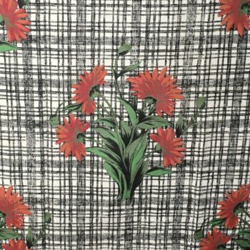 Toile d’ameublement vintage des années 1960s, en coton. Le dessin montre un bouquet de quatre marguerites rouges sur fond blanc strié et quadrillé de noir.