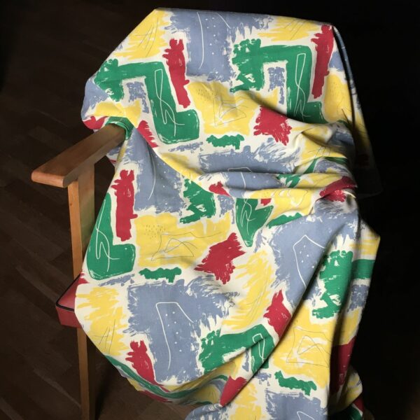 Toile d’ameublement vintage des années 1950s. L’imprimé graphique montre des formes libres en couleurs franches, jaune, vert, rouge, bleu, avec effets de crayonné, sur fond jaune pâle ou blanc crème ivoire. Coupon neuf d’époque, stock dormant.