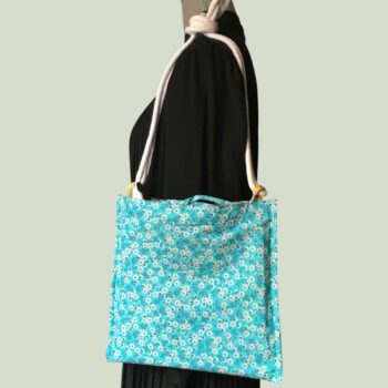 Sac bandoulière à imprimé fleuri, en tissu vintage. Au verso la doublure est un tissu 100% coton à motif de petites fleurs blanches sur fond bleu ciel.