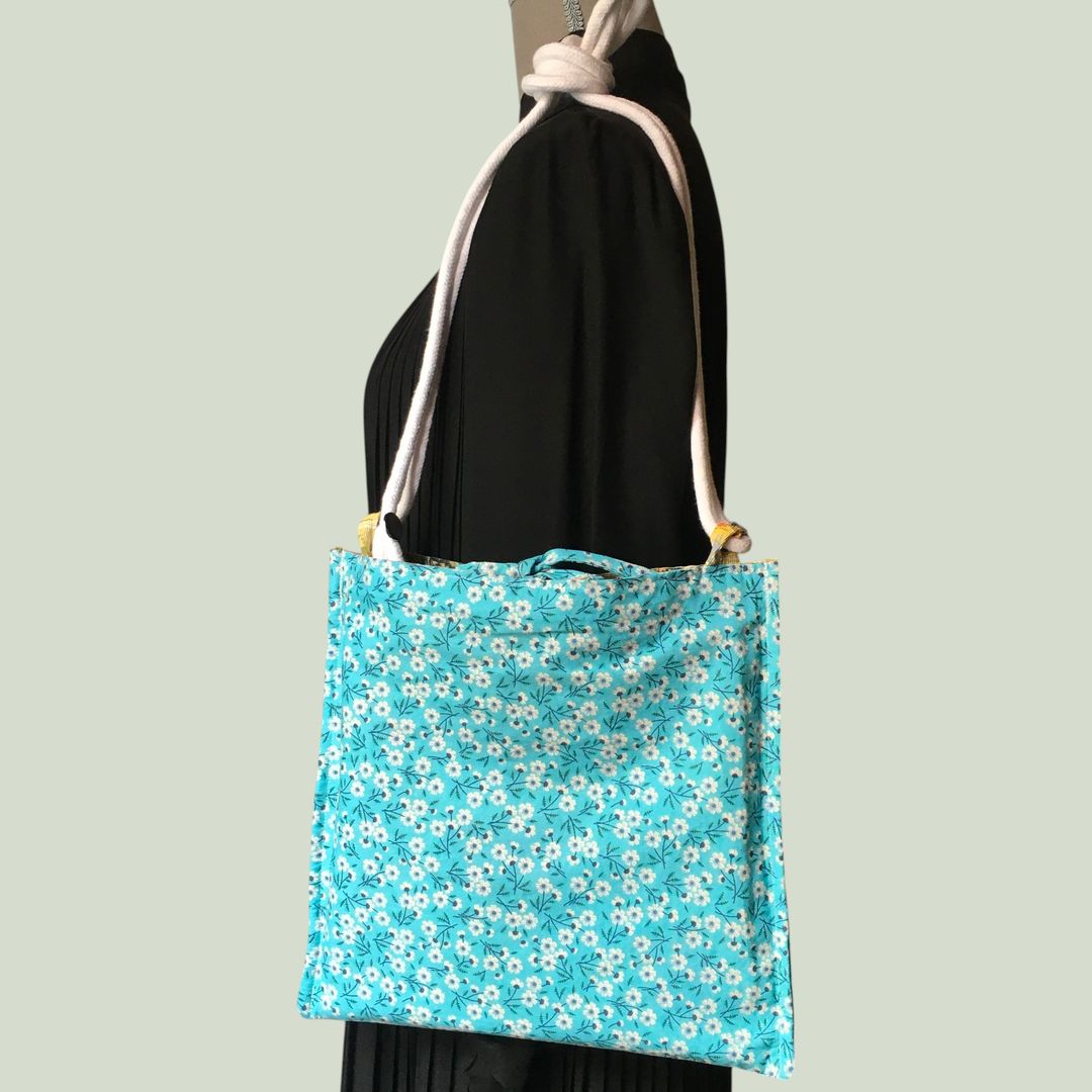 Sac bandoulière à imprimé fleuri, en tissu vintage. Au verso la doublure est un tissu 100% coton à motif de petites fleurs blanches sur fond bleu ciel.