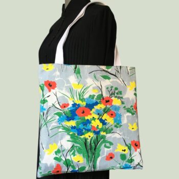 Totebag fleuri, à dessin de fleurs stylisées. Au recto le sac présente une toile de coton texturé (barkcloth), un imprimé de bouquets de fleurs stylisées en rouge bleu jaune vert sur fond blanc et gris.